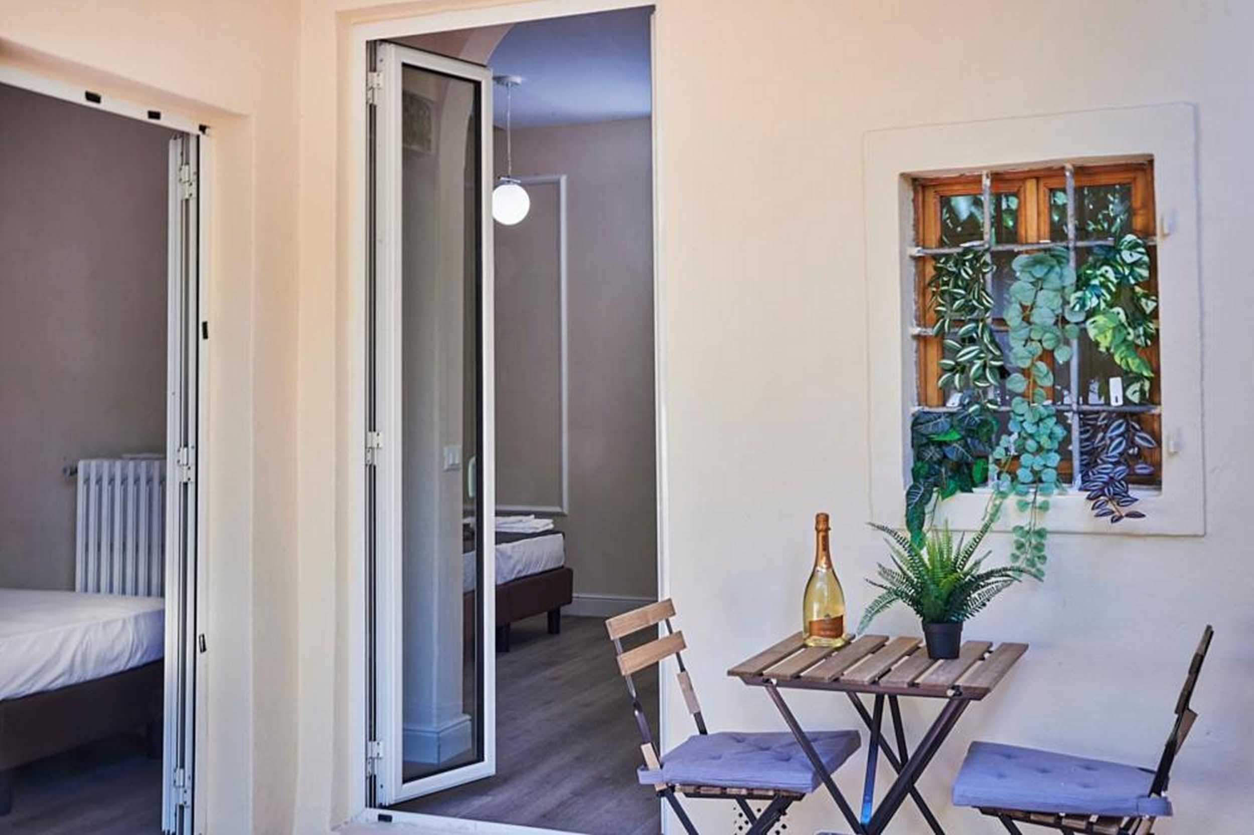 Tavolino con due sedie e bottiglia di vino nel patio privato di El Roy Garden Rooms